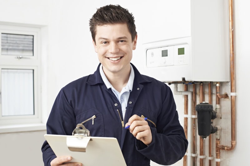 Male Plumber Working On Central Heating Boiler.