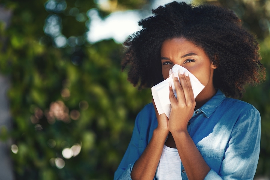 Woman blowing nose from seasonal allergies