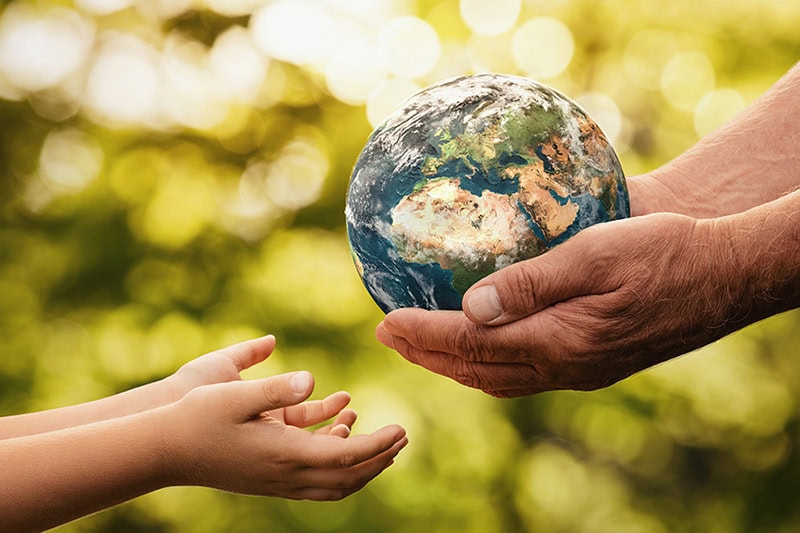 What Does a Geothermal System Cost? Photo of a pair of adult hands giving a child a globe of the world.