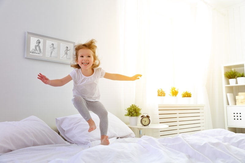 happy child girl having fun jumps and plays bed